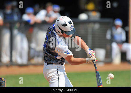 During a high school baseball game, a batter swings while making solid contact. USA. Stock Photo
