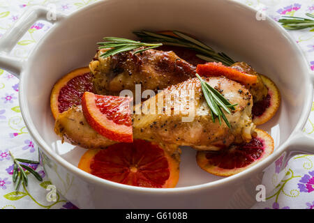 Roasted chicken legs on slices of red oranges in white baking dish. Cooked with the sauce: orange juice, mustard, olive oil Stock Photo
