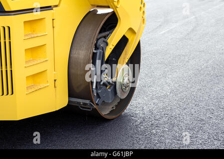 Yellow road roller leveling new asphalt on road Stock Photo