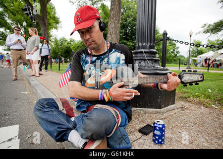 Man sitting on sidewalk playing guitar - USA Stock Photo