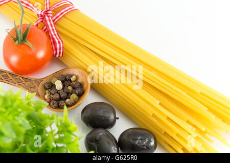 Uncooked spaghetti pasta with vegetables against white background Stock Photo