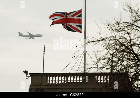 A British Airways plane flies past a flag flying at half-mast at Horse Guards Parade, central London, for the funeral service of Baroness Thatcher, that took place at St Paul's Cathedral in central London. Stock Photo