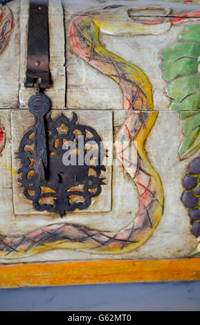 A charming & whimsical folk art style wood carved trunk depicting snakes and grapes and birds with decorative metal lock plate Stock Photo