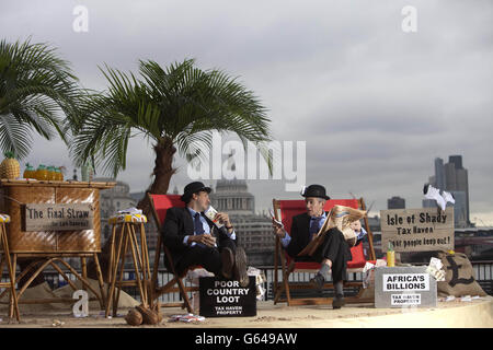 Luke Harman (left) and Mark Webber, dressed as bankers, sit on The Isle of Shady, a pop-up tax haven set up by Enough Food for Everyone IF campaigners, sits on the South Bank of the river Thames at Gabriel's Wharf in London ahead of the Open for Growth: Tax, Trade and Transparency event on 15th June and the G8 summit. PRESS ASSOCIATION Picture date: Friday June 14, 2013. Enough Food for Everyone IF is a coalition of more than 200 organisations working together to ensure that governments tackle causes of the global hunger crisis in the year that the UK Government hosts the G8 leaders. Photo Stock Photo