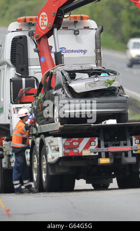 The grey Renault Clio is removed from the scene on the A419 near Swindon, after it careered off the road into undergrowth. A teenage driver and her female passenger have died in the accident and three men are in hospital. Stock Photo