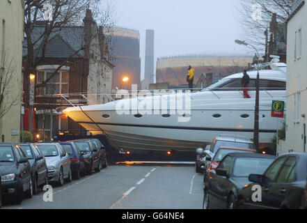 A boat on the back of a flat-bed lorry makes its way up Wandsworth Bridge Road in London towards Earls Court exhibition centre. The venue is hosting the forthcoming London Boat Show which begins on January 2. Stock Photo