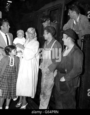 Hollywood actress Jayne Mansfield proudly holds her eight-months-old son Miklos Hargitay as she chats to railwaymen on a platform at Euston station. Also seen with the actress are her husband Mickey Hargitay and eight-year-old Jayne Marie, daughter of her first marriage to Paul Mansfield. Stock Photo