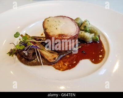 Free range bacon wrapped chicken with garlic gnocchi, served as part of a gourmet menu Stock Photo