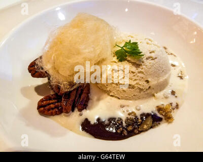 Bourbon marshmallow ice cream on a bed of dark chocolate pudding with caramel pecans, served during gourmet dinner Stock Photo