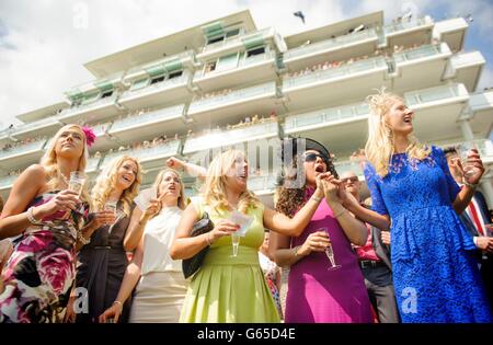 Racegoers react as they watch the racing during the Investec Ladies Day at Epsom Downs Racecourse, Surrey. Stock Photo