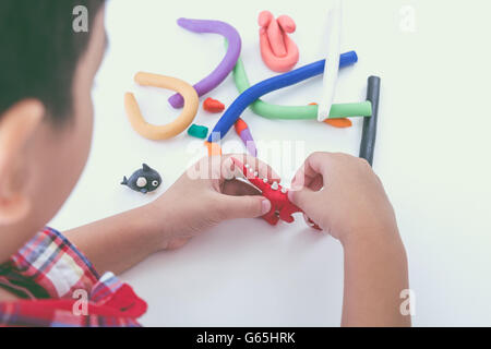 Little asian boy playing and creating toys from play dough. Child molding model clay. Strengthen the imagination of child. Stock Photo