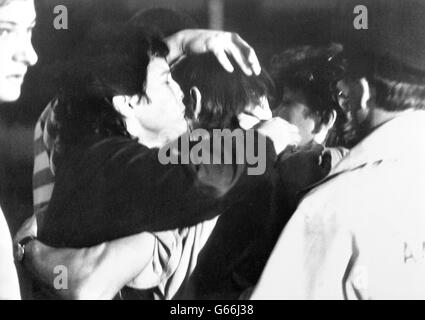 A survivor of the explosion disaster on the North Sea oil production platform Piper Alpha embraces loved ones after landing at Aberdeen. Stock Photo