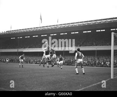 Ipswich Town goalkeeper Roy Bailey punches the ball clear of Arsenal's Geoff Strong and Ipswich Town teammates George Dougan and Andy Nelson. Stock Photo