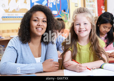 Portrait Of Teacher With Female Elementary School Pupil In Class Stock Photo