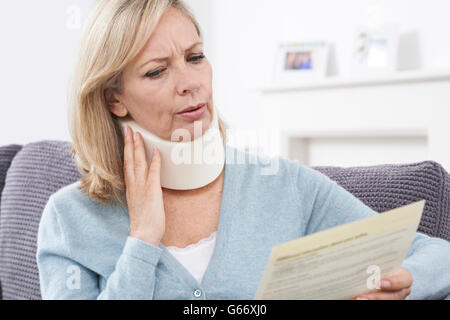 Mature Woman Reading Letter After Receiving Neck Injury Stock Photo