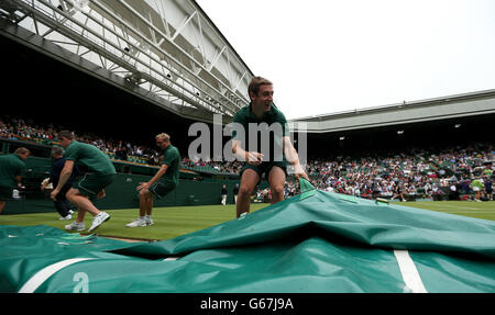 Groundstaff race to put the covers on centre court as rain stops play during the match between Poland's Agnieszka Radwanska and France's Mathilde Johansson Stock Photo