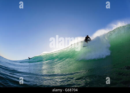 Surfer unidentified silhouetted surfing water action closeup swimming photo. Stock Photo