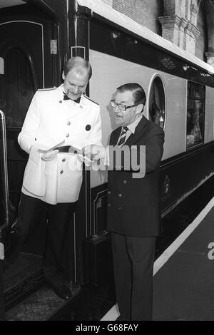 Travel journalist Alan Whicker checks his ticket with a porter before boarding the Venice-Simplon Orient Express, which is leaving from Victoria Station, London, for its inaugural trip. The British section of the journey to Folkestone is in all-Pullman veteran carriages restored to pristine condition. Stock Photo