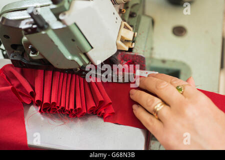 Hands of a seamstress stitching red cloth on sewing machine Stock Photo