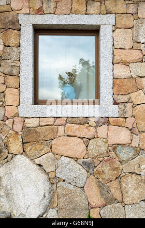 Open window on a block of granite wall with a vase of ears of corn. Stock Photo