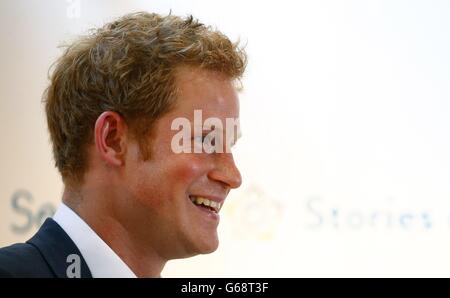 Prince Harry makes a joke about the hot temperature during a speech at the private view of the 'Sentebale - Stories of Hope' exhibition of photographs in central London. PRESS ASSOCIATION Photo. Picture date: Thursday July 25, 2013. Prince Harry declared tonight he was ready to play the proud, protective uncle for his new nephew Prince George and 'make sure he has fun'. Harry could not stop beaming as he talked about the newest member of his family during his visit to a photographic exhibition in London documenting the work of his Africa-based charity Sentebale. Asked what his mission was as Stock Photo