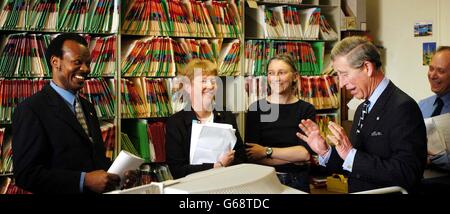 The Prince of Wales, visits the Red Cross in London. Following the death of his grandmother, The Queen Mother, last year, he has taken on her role as President of this charity. Prince Charles talks with tracing case worker Albino Okello (far left) Stock Photo