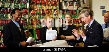 The Prince of Wales, visits the Red Cross in London. Following the death of his grandmother, The Queen Mother, last year, he has taken on her role as President of this charity. Prince Charles talks with tracing case worker Albino Okello (far left). Stock Photo