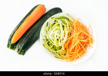 Two zucchini courgettes and carrot with some spiralized in white bowl on white background Stock Photo