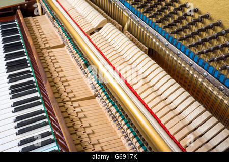 Action mechanics close up inside of an upright piano. Pattern of keys, shanks, hammers and strings. Stock Photo