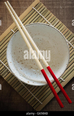 Japanese ceramic rice or noodle bowl with red handled bamboo chopsticks Stock Photo