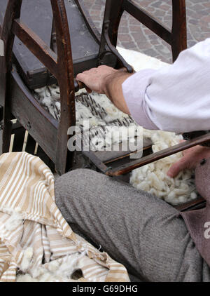 Senior carder man while carding wool or cotton with old wooden machine ...