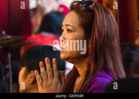 Emotional Vietnamese woman praying at a temple Stock Photo