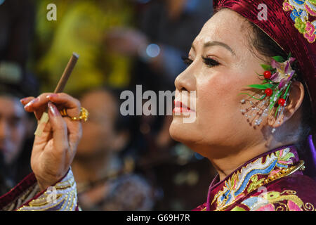 Female medium smokes while preparing for spirit mediumship ritual in Vietnam Stock Photo