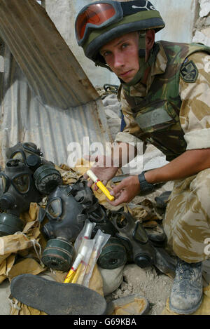 Lieutenant Gareth Dent from 9 Squadron Royal Engineers attached to The 1st Battalion The Parachute Regiment displays a stockpile of chemical warfare suits, respirators, and Atropine pens found at a former army camp in Ad Dayr, a small village north of Basra, Iraq. * Atropine is an antidote injected into people exposed to nerve agent. Stock Photo