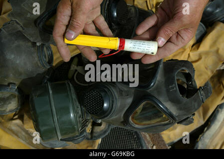 Lieutenant Gareth Dent from 9 Squadron Royal Engineers attached to The 1st Battalion The Parachute Regiment displays, part of a stockpile of chemical warfare suits, respirators, and Atropine pens found at a former army camp in Ad Dayr, a small village north of Basra, Iraq. *..Atropine is an antidote injected into people exposed to nerve agent. Stock Photo