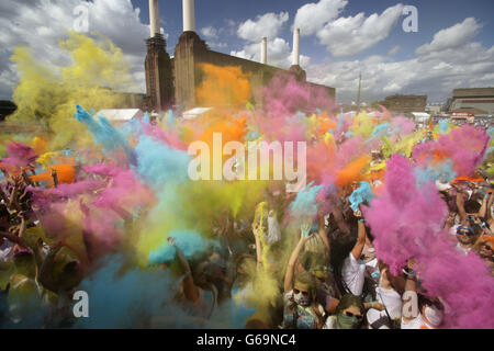 People throwing brightly coloured powder in the air during the Holi One Festival, at Battersea Power Station in London. Stock Photo