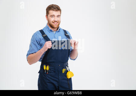 Smiling handsome male builder standing isolated on a white background and looking at camera Stock Photo