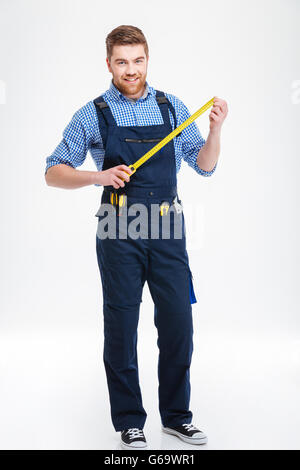 Smiling young worker standing and holding masuring tape Stock Photo