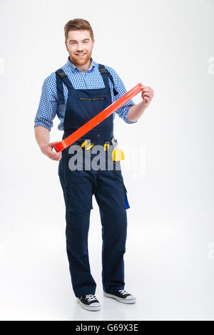 Happy bearded worker standing and using red adhesive tape Stock Photo
