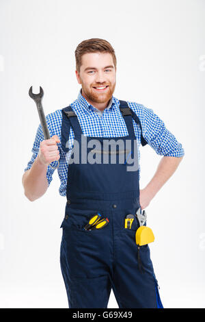 Cheerful attractive young worker in overall holding wrench Stock Photo