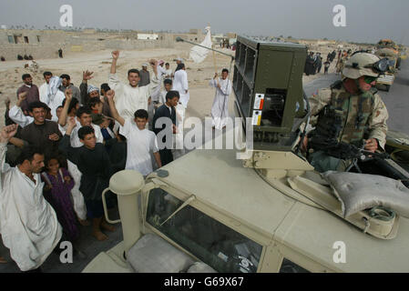 Iraqi men and children celebrate as they listen to loud speakers from a US Marines psychological operations vehicle attached to The 1st Battalion The Parachute Regiment in the village of Ad Dayr north of Basra. Stock Photo