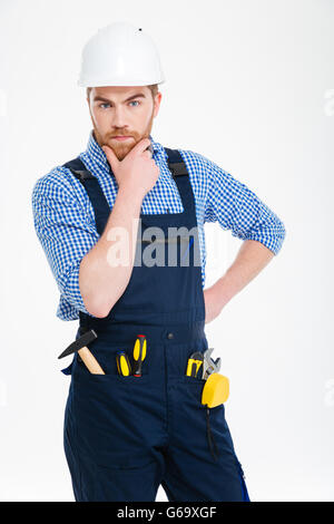Thoughtful serious young builder standing and thinking Stock Photo
