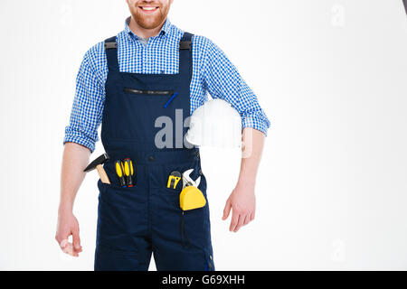 Smiling young worker in overall holding his helmet Stock Photo