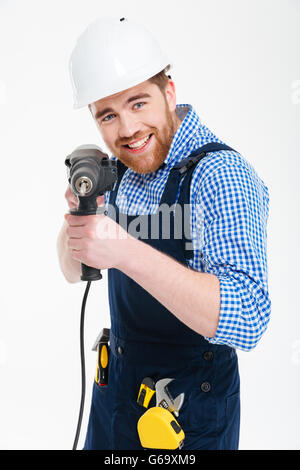 Smiling bearded young man using drill and pointing on you Stock Photo
