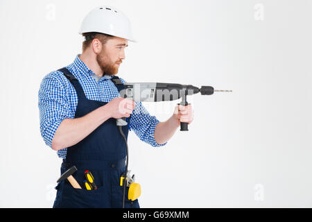 Profile of concentrated handsome young builder using modern drill Stock Photo