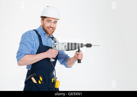 Happy attractive young builder smiling and using modern drill Stock Photo