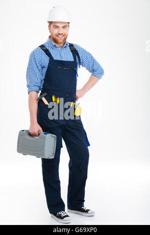 Full length of cheerful young builder standing and holding tool box Stock Photo