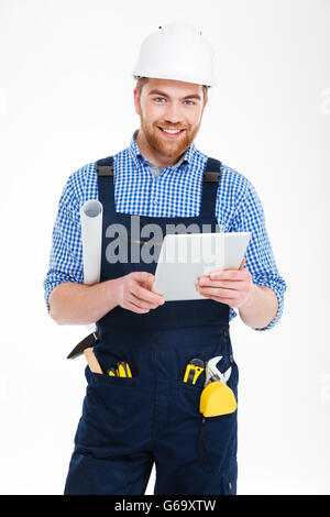 Cheerful attractive bearded man in helmet smiling and using tablet Stock Photo