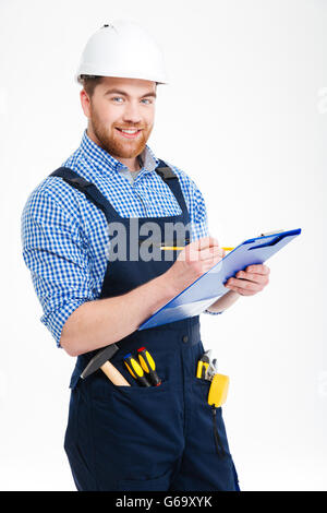 Happy confident young builder writing and using clipboard Stock Photo