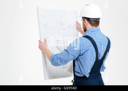 Back view of man builder in helmet working with blueprint Stock Photo